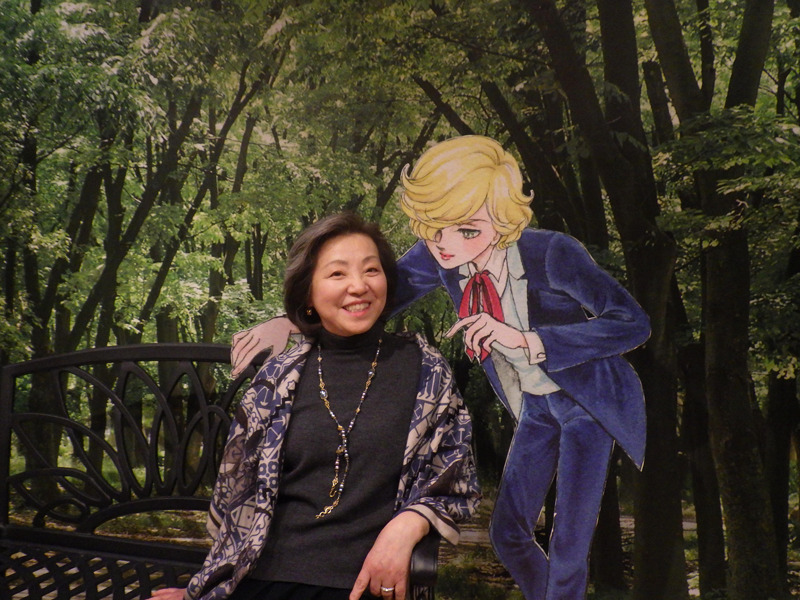 Keiko Takeimiya sits on a park bench next to a cut-out stand of Gilbert at her exhibition. 